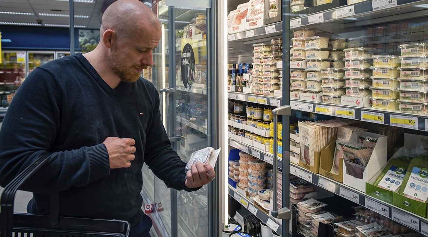 mand kigger på fødevarer i supermarkedets køledisk
